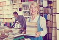 Smiling mature woman holding book pile