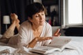 Smiling mature woman reading book while lying on bed Royalty Free Stock Photo