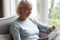 Smiling mature woman reading book, sitting on couch at home Royalty Free Stock Photo