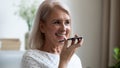 Smiling mature woman recording voice message on phone close up Royalty Free Stock Photo