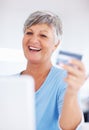 Smiling mature woman shopping online. Smiling mature woman shopping online using credit card and laptop. Royalty Free Stock Photo