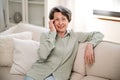 smiling mature woman sitting on cozy couch at home Royalty Free Stock Photo