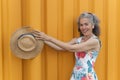 Smiling mature woman with straw hat Yellow background Royalty Free Stock Photo