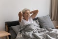 Smiling mature woman stretching after awakening in cozy bed Royalty Free Stock Photo