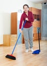 Smiling mature woman sweeping the floor Royalty Free Stock Photo