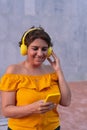 Smiling mature woman using cell phone while listening to music with headphones in the street Royalty Free Stock Photo