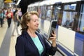 Smiling mature woman using eBook in subway while waiting train at metro station Royalty Free Stock Photo