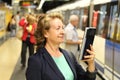 Smiling mature woman using eBook in subway while waiting train at metro station Royalty Free Stock Photo