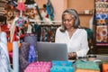 Smiling mature woman using a laptop in her fabric shop Royalty Free Stock Photo