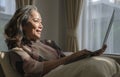 Smiling mature woman using laptop, working, chatting, spending time in social media internet while sitting on sofa at home Royalty Free Stock Photo