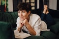 Smiling mature woman reading book while lying on couch Royalty Free Stock Photo