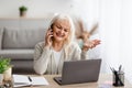 Smiling mature woman working and talking on phone at home Royalty Free Stock Photo