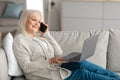 Smiling mature woman working and talking on phone at home Royalty Free Stock Photo