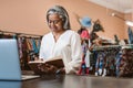 Smiling mature woman writing notes in her fabric shop Royalty Free Stock Photo