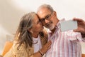 Smiling mature woman and man in casual make selfie on smartphone, enjoy date together in cafe table Royalty Free Stock Photo