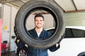 Smiling Mechanic Looking Through Car Tire In Auto Repair Shop