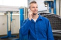 Smiling mechanic on the phone Royalty Free Stock Photo