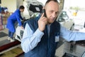 Smiling mechanic on phone at repair garage Royalty Free Stock Photo