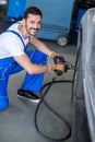 Smiling mechanic repairing car wheel
