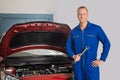 Smiling Mechanic Standing In Front Of Car