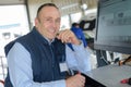 Smiling mechanic using computer at repair garage Royalty Free Stock Photo