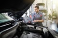 Smiling young man mechanic using a laptop computer to check a car engine Royalty Free Stock Photo