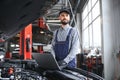 Smiling mechanic using a laptop pc at the repair garage. Royalty Free Stock Photo