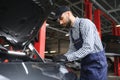 Smiling mechanic using a laptop pc at the repair garage. Royalty Free Stock Photo