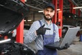 Smiling mechanic using a laptop pc at the repair garage. Royalty Free Stock Photo