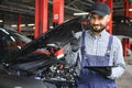 Smiling mechanic using a tablet pc at the repair garage. Royalty Free Stock Photo