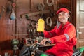 Smiling mechanic wearing wearpacks and hats riding motorbikes while carrying oil bottles