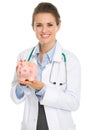 Smiling medical doctor woman holding piggy bank