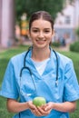 smiling medical student holding apple in hands and looking Royalty Free Stock Photo