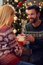 Man presenting Christmas gift to happy young woman at home