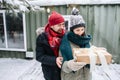 Smiling man in winter clothes gifted woman with a present in a bow-tied box