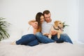 Smiling man and woman sitting on floor at home with their pet dog. Portrait of happy dog loving family with their pet dog Royalty Free Stock Photo