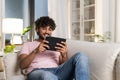 A smiling mestizo guy reclining on the sofa in the room, enjoys relax after work or study in the cozy home environment Royalty Free Stock Photo