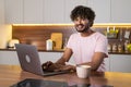 A smiling mestizo young man in the kitchen in subdued lighting, holds a bowl of pasta in hands, wraps them in a fork. An