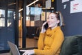 Smiling mid adult caucasian businesswoman talking on smartphone while sitting with laptop in office Royalty Free Stock Photo