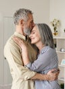 Smiling mid age older couple hugging and kissing standing at home. Royalty Free Stock Photo