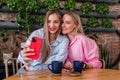 Smiling mid age women friends taking selfie at cafe with mobile phone on plants background. Caucasian girls indoors Royalty Free Stock Photo