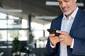 Smiling mid aged business man wearing suit standing in office using cell phone. Royalty Free Stock Photo