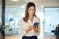 Smiling mid aged business woman executive using smartphone standing in office. Royalty Free Stock Photo