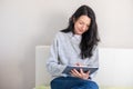 Smiling mid aged woman in grey sweater holds a tablet, reading or working, exemplifying digital literacy and comfort at Royalty Free Stock Photo