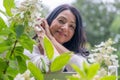 A smiling midage woman in a green flower garden is expressing happiness and joy of midlife hormonal changes and