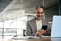 Smiling middle aged business man sitting in office using mobile phone. Royalty Free Stock Photo