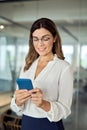 Smiling middle aged business woman holding cell phone standing in office. Royalty Free Stock Photo