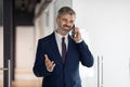 Smiling Middle Aged Businessman Talking On Cellphone While Walking Out Of Office Royalty Free Stock Photo