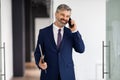 Smiling Middle Aged Businessman Talking On Cellphone While Walking Out Of Office Royalty Free Stock Photo