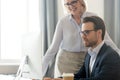 Smiling middle-aged businesswoman help male employee working on pc Royalty Free Stock Photo